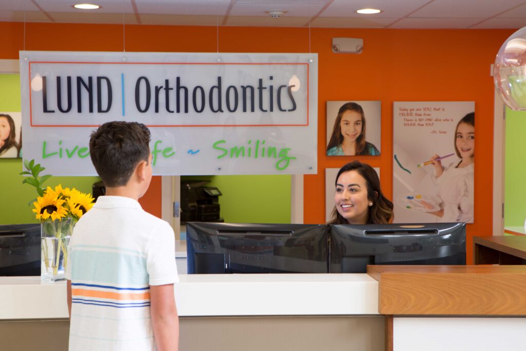 a boy talking to the Lund orthodontics receptionist at their front desk