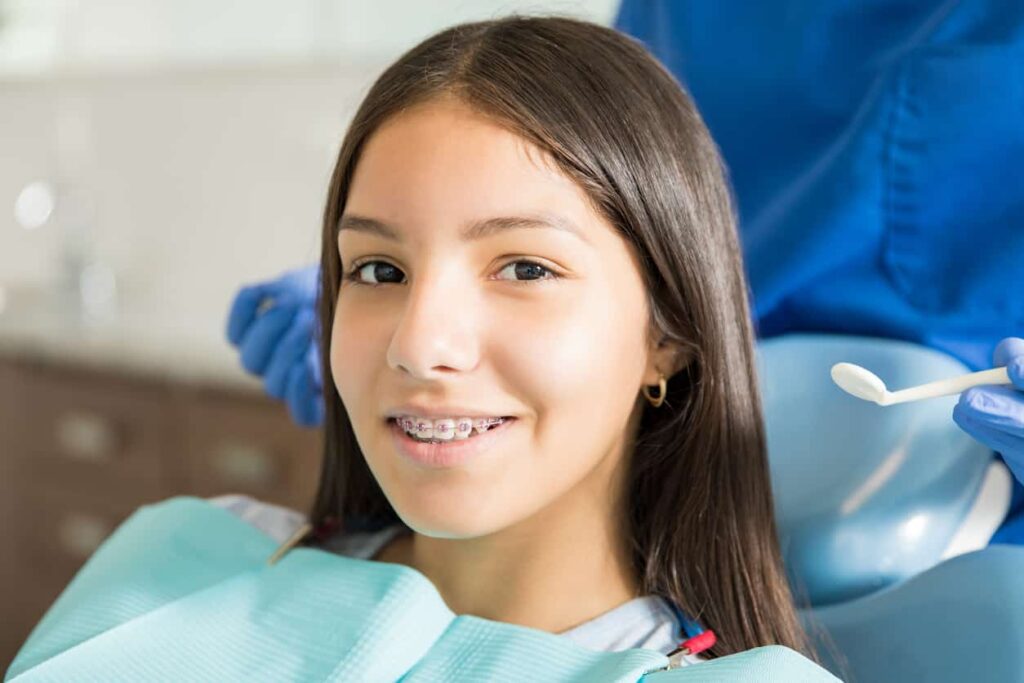 a teenage girl sitting on the orthodontic chair while she recieves orthodontic care