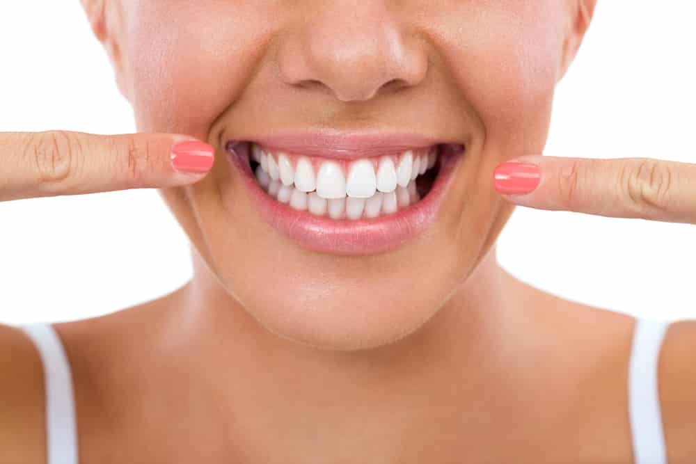 a woman showing off her white straight teeth after receiving orthodontic treatment