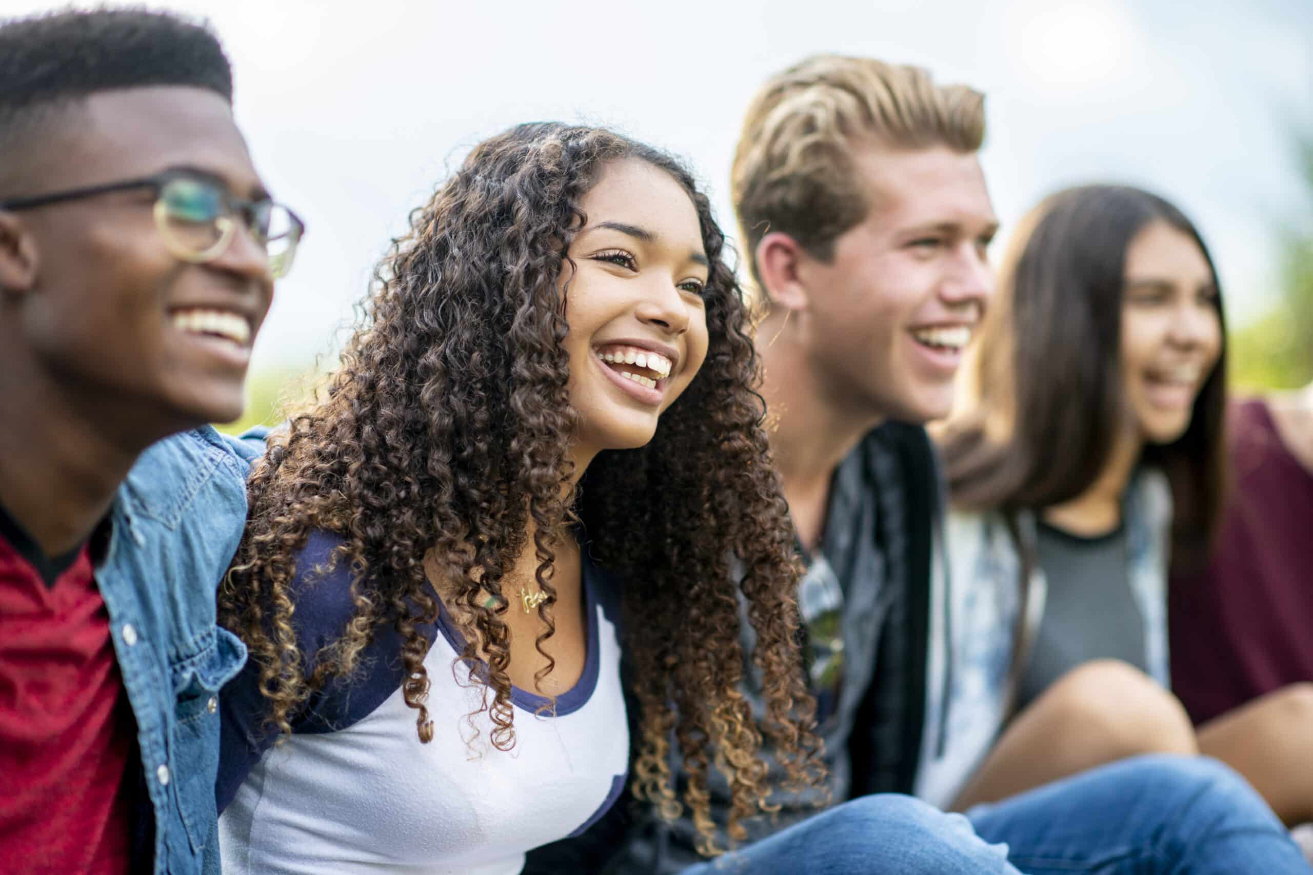 four smiling teenagers with their arms around eachother
