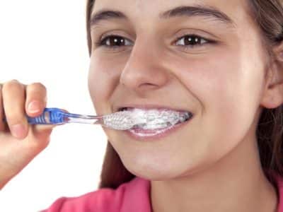 eenage girl brushing her teeth and braces